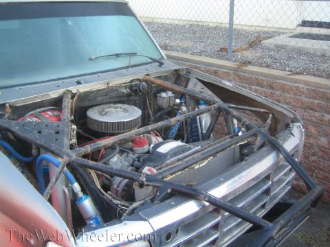 1990 Ford Bronco - Open engine bay of a project truck showing a V8 with chrome air cleaner, blue ignition wires, and tubular front framing.