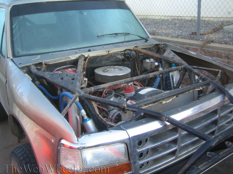 Engine bay of a truck with V8, chrome air cleaner, and exposed front grille framing