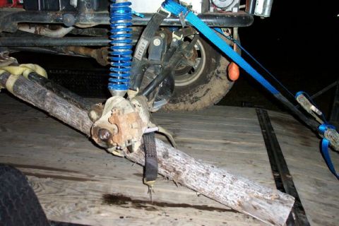 1990 Ford Bronco - Vehicle suspension part is strapped down for transport on a trailer.