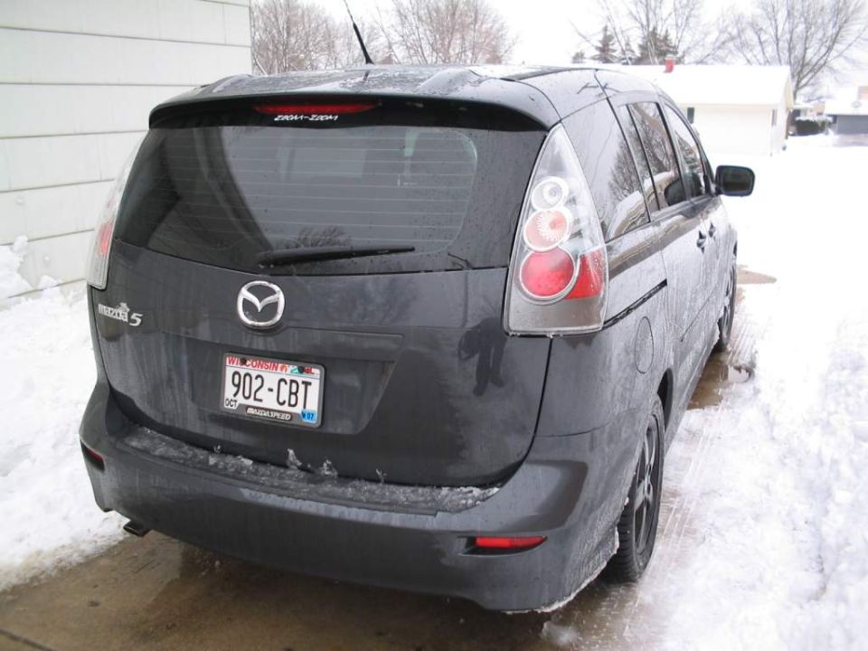 Dirty dark gray Mazda 5 minivan rear view in a snowy driveway with Wisconsin plate 902-CBT