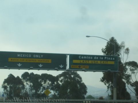 1990 Ford Bronco - Overhead green freeway signs near the border read "Mexico Only - Watch for Stopped Vehicles" and "Camino de la Plaza, Last USA Exit" under…