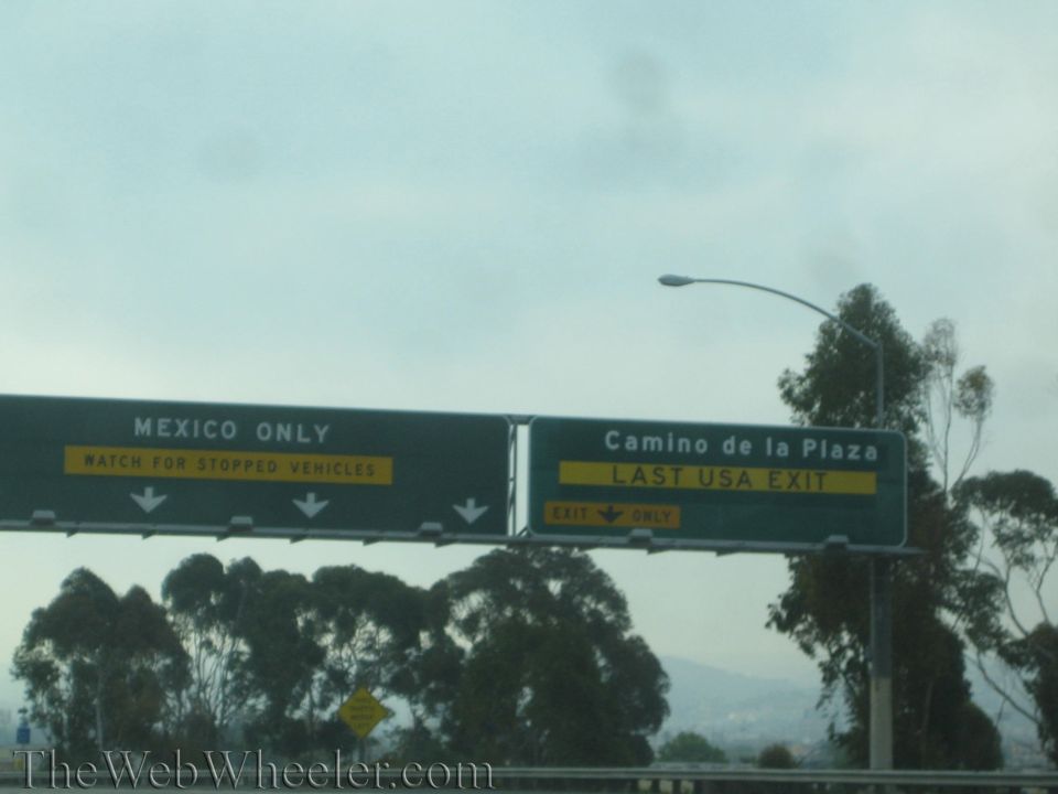 Highway overhead green signs reading Mexico Only and Camino de la Plaza Last USA Exit
