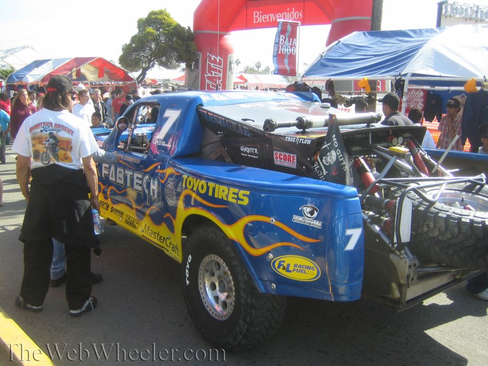 Blue number 7 Fabtech Toyo Tires off-road race truck at a pit area