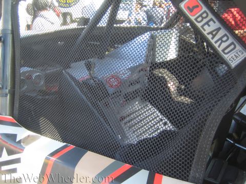 1990 Ford Bronco - Close-up through a black mesh window net of a race vehicle interior, showing a Beard Seats sticker at upper right.