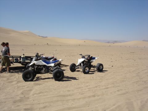 1996 Ford Bronco - Two ATVs sit on a sandy terrain with dunes in the background.