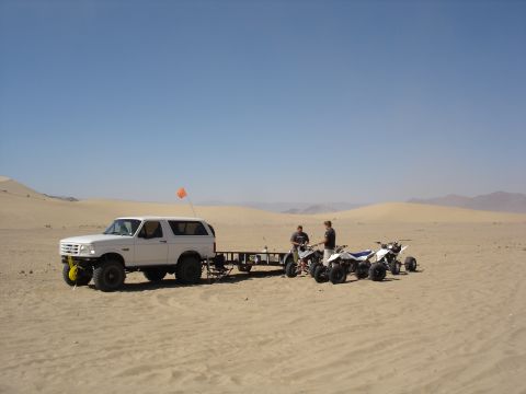 1996 Ford Bronco - 1996 Ford Bronco with trailer and ATVs parked in the desert under a clear blue sky.