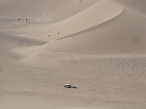 1996 Ford Bronco - A lone vehicle navigates the vast sand dunes, towing a trailer across the sandy terrain.