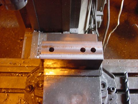 1994 Ford Bronco - A metal component with three drilled holes is being machined.