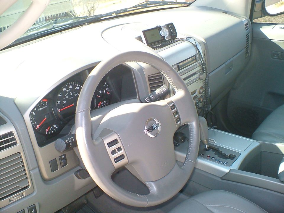 Tan interior of a Nissan SUV showing steering wheel, gauges, and center console