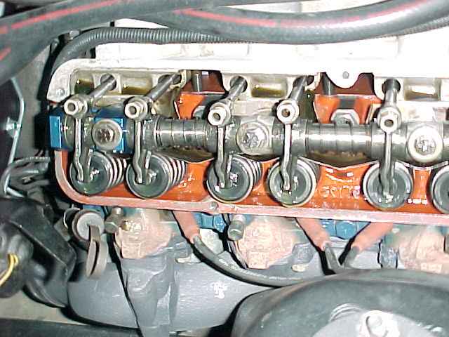 Exposed rocker arms and valve springs on orange-painted cylinder head with valve cover removed