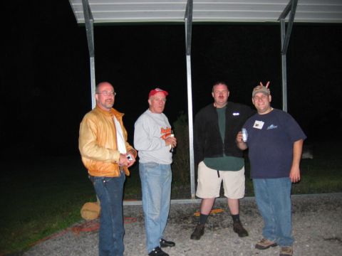 1985 Ford LTD Crown Victoria - Four men are gathered outdoors at night under a covered structure, with one man playfully making bunny ears.