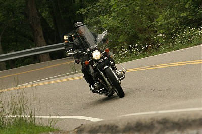 1985 Ford LTD Crown Victoria - A motorcycle navigates a sharp turn on a scenic road.