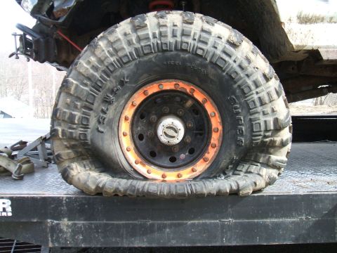 1995 Ford Bronco - A flat tire with an orange rim is visible on a trailer, indicating damage.