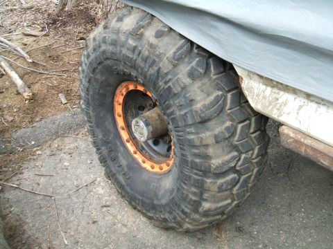 1995 Ford Bronco - Close-up of a large off-road tire on a vehicle, partially covered by a tarp.