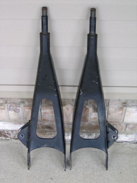 1989 Ford Bronco - A pair of black control arms are shown against a brick and siding background.