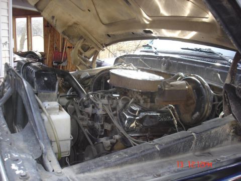 1979 Ford Bronco - The engine bay of a vehicle is shown, a V8 engine with an air cleaner and various hoses and wires.