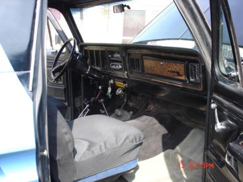1979 Ford Bronco - The interior of a 1979 Ford Bronco shows its dashboard with wood grain accents and a black steering wheel.