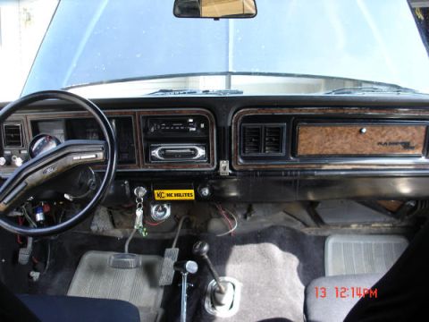 1979 Ford Bronco - The interior of a classic Ford vehicle features wood grain trim, a cassette player, and a manual transmission shifter.