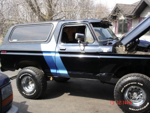 1979 Ford Bronco - This 1979 Ford Bronco features a distinctive blue stripe along its side and has its hood propped open.