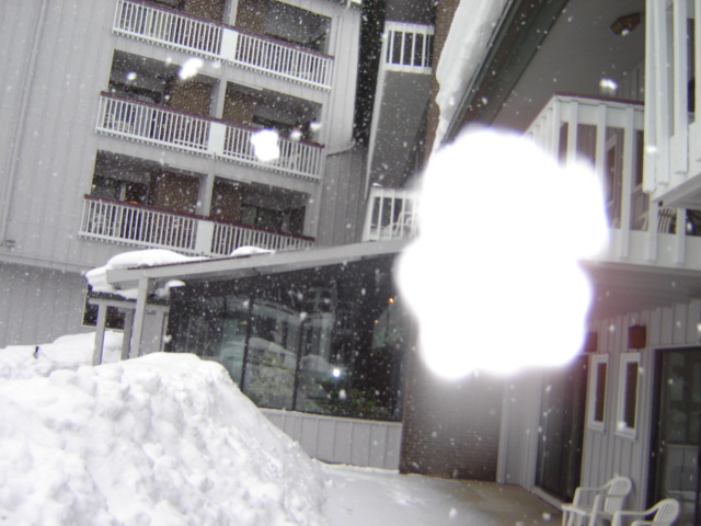 Building with balconies covered in snow, with a bright light obscuring part of the scene