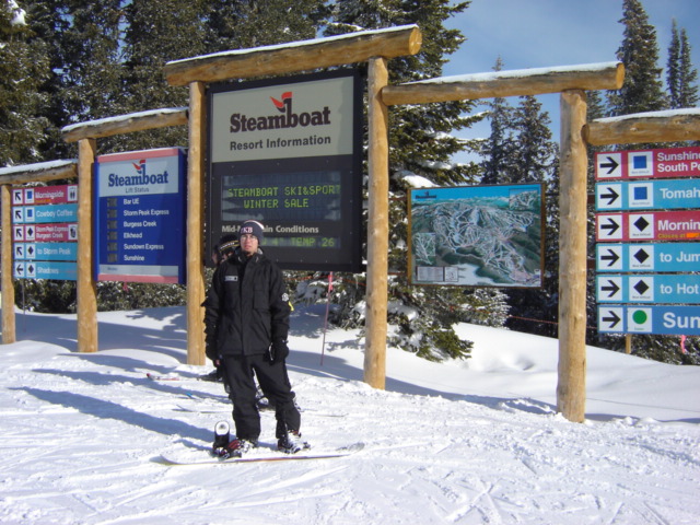 Snowboarder in front of Steamboat Resort Information sign and trail map