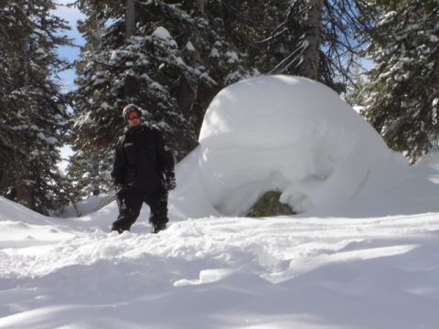 1992 Ford Bronco - A person stands in a snowy forest next to a large snow formation.