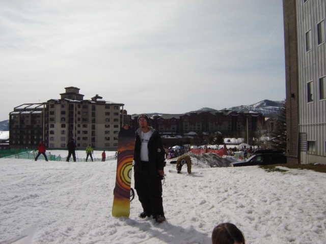 Man with snowboard in snowy landscape with buildings and mountains
