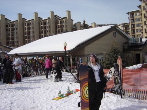 1992 Ford Bronco - Ski resort scene with people and winter sports equipment. A man stands with a snowboard.
