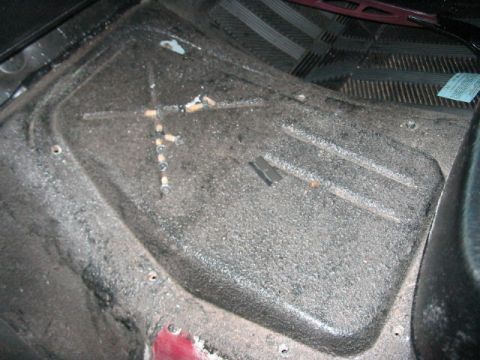 1991 Ford Bronco - The interior floor of a vehicle shows a textured surface with debris and cigarette butts.