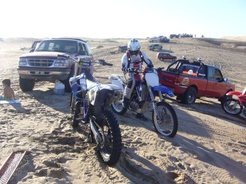1996 Ford Explorer - A red 1996 Ford Explorer is parked on a sand dune with dirt bikes and people nearby.