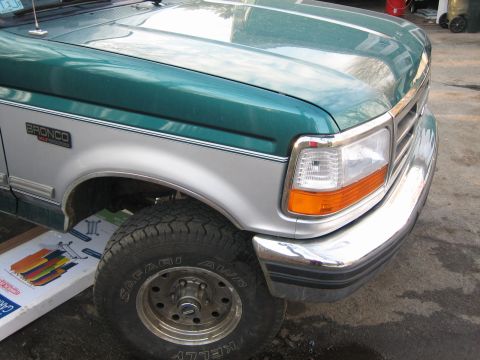 1994 Ford Bronco - Close-up of a Ford Bronco's front passenger side, showing the fender, headlight, and tire.