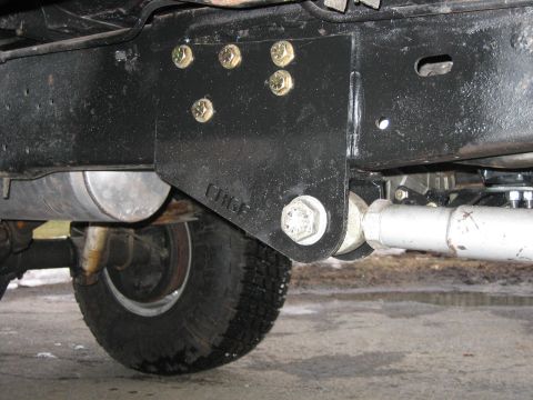 1994 Ford Bronco - Close-up view of aftermarket suspension bracket and components attached to a vehicle's frame.