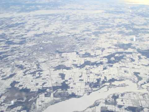 1996 Ford Bronco - An aerial perspective captures a vast, snow-blanketed terrain dissected by a meandering river, with a city visible in the distance.