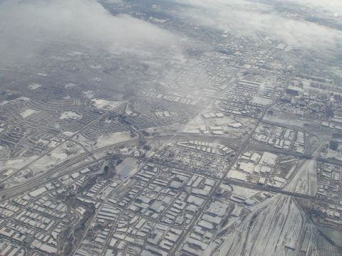 1996 Ford Bronco - An aerial view shows a city blanketed in snow, with roads and buildings visible beneath a layer of white.
