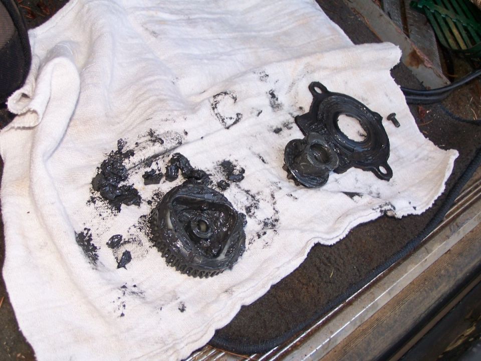 Greasy disassembled gear and housing parts on a white rag