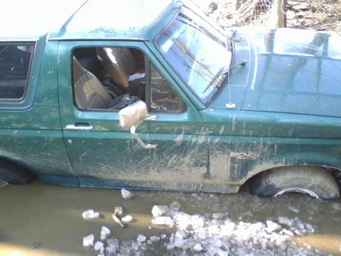1996 Ford Bronco - Muddy 1996 Ford Bronco stuck in water, showing side profile and "BRONCO" emblem.