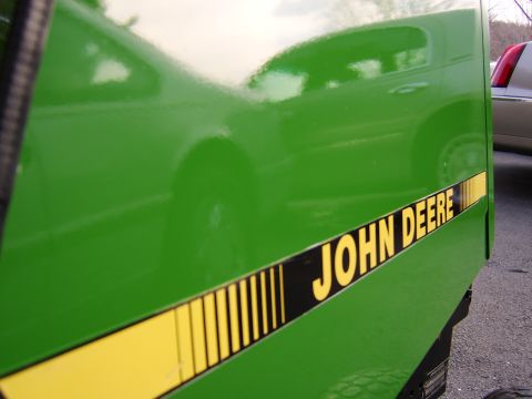 1996 Mercury Grand Marquis - Side view of a green John Deere tractor panel, showing the brand name and a reflection.