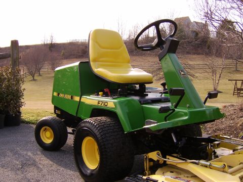 1996 Mercury Grand Marquis - A green and yellow John Deere F710 lawn tractor sits parked on a gravel surface with a rural background.