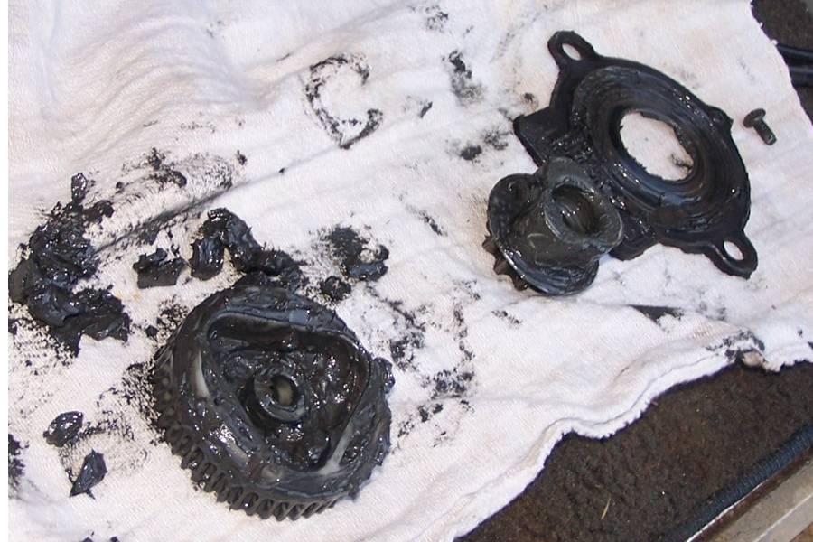 Close-up of grease-covered gear and housing on a rag