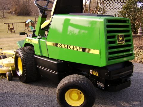 1996 Mercury Grand Marquis - A green John Deere F710 riding mower is parked on a driveway next to a yellow mower deck.