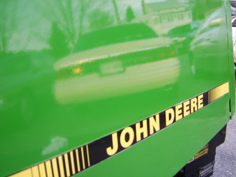 1996 Mercury Grand Marquis - A green John Deere tractor is shown with a reflection of a white car in its glossy surface.