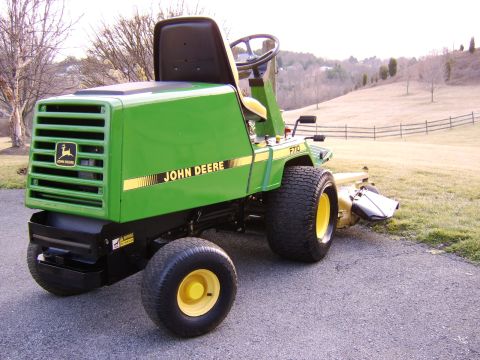 1996 Mercury Grand Marquis - A green John Deere F710 riding mower is parked on a paved surface with a grassy hill in the background.