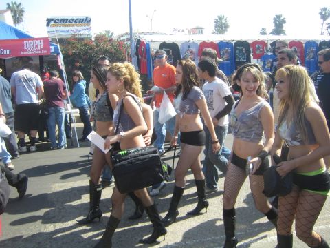 1990 Ford Bronco - group of young women in matching tops and shorts walk past T-shirt vendor tents at a sunny outdoor event.