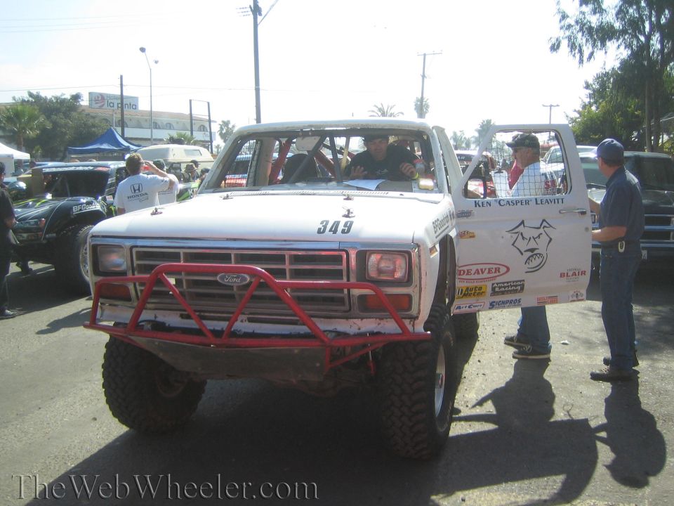 White off-road race truck number 349 with red tube bumper and Ford grille at staging area