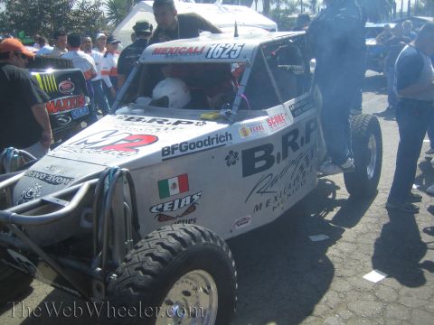 1990 Ford Bronco - white open-cockpit off-road race buggy numbered 1625 with 'B.R.P. Racing' lettering and a Mexican flag decal sits amid a crowd.