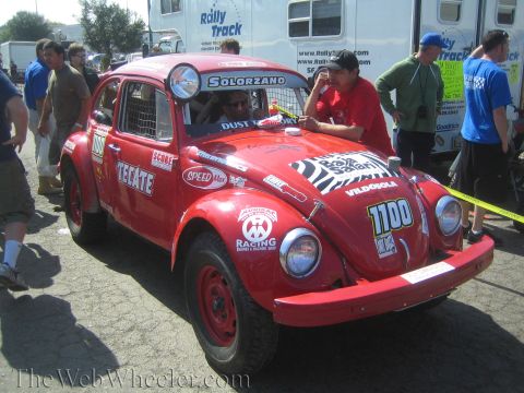 1990 Ford Bronco - red Baja Bug built from a Volkswagen Beetle, numbered 1700 with Tecate and 'Solorzano' lettering, parked at a contingency event.