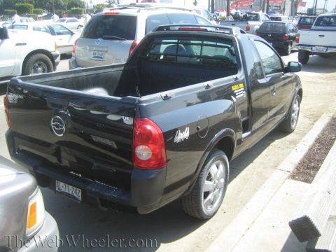1990 Ford Bronco - black compact car-based pickup with a sport bar is parked at an angle on a street lined with other vehicles.