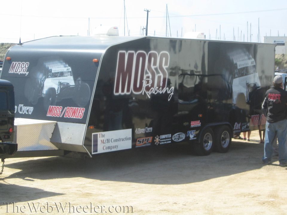 Black and silver enclosed race trailer lettered Moss Racing on a dirt lot