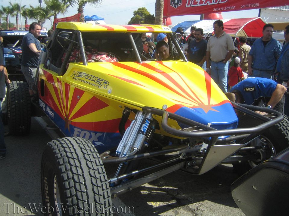 Yellow and blue race buggy with sunburst graphic and Fox shock surrounded by crowd