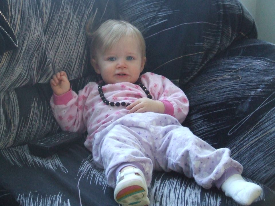 Baby girl in pajamas sitting on a couch